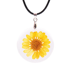 A vibrant yellow daisy set in a white glass pendant, showcased on a stylish round cord necklace.