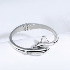 A stylish silver-plated hinged bangle adorned with a dolphin design, perfect for ocean lovers and fashion enthusiasts alike.