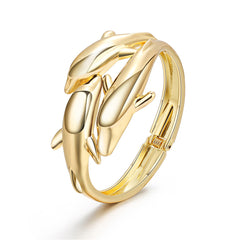 A gold-plated bracelet featuring a tri-dolphin design, elegantly bypassing the wrist in 18K gold.