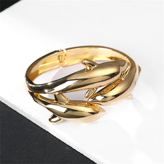 An elegant 18K gold-plated bracelet adorned with two dolphins, designed in a bypass style for a sophisticated look.