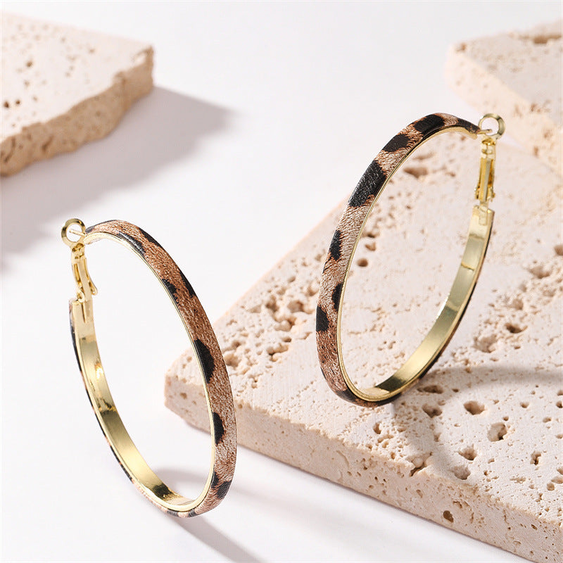 Stylish gold hoop earrings adorned with black and white dots, showcasing a trendy leopard print design.