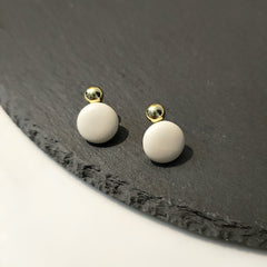 A pair of gold-plated round drop earrings in ivory leather highlights their stylish elegance.