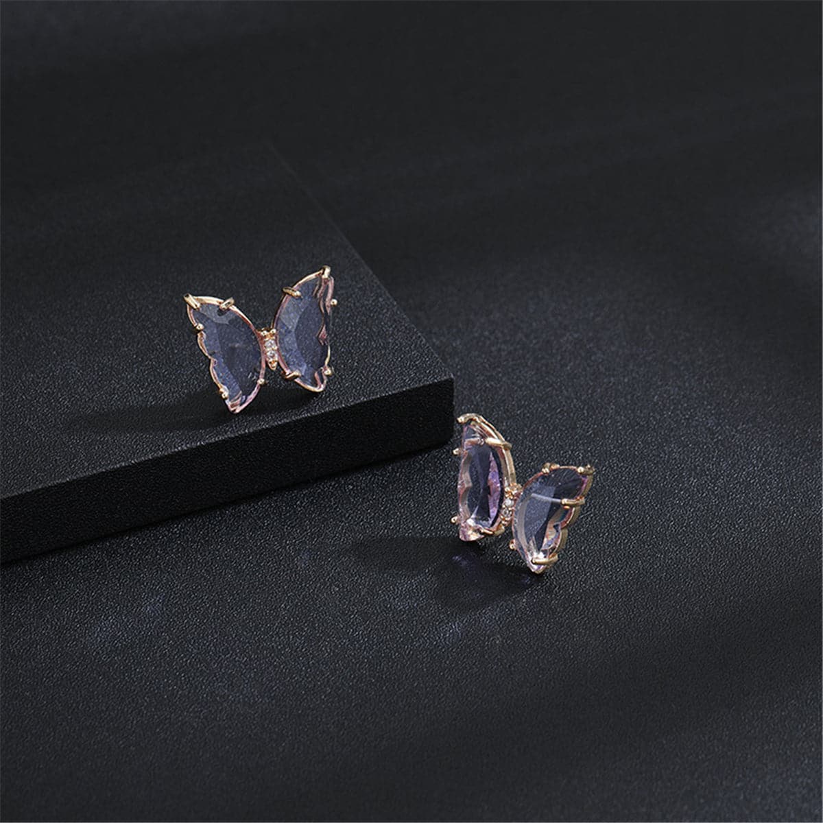 Two butterfly earrings with rose gold-plated accents, featuring purple crystals and an elegant design.
