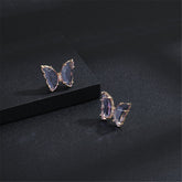 Two butterfly earrings with rose gold-plated accents, featuring purple crystals and an elegant design.