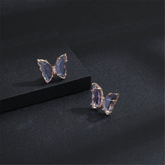 Two butterfly earrings with rose gold-plated accents, featuring purple crystals and an elegant design.