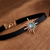 A black choker featuring a sunburst stone, crafted with crystal and cubic zirconia, and 18k gold-plated accents.