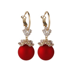 Elegant red ball earrings adorned with cubic zirconia, set in 18k gold-plated flower huggies.