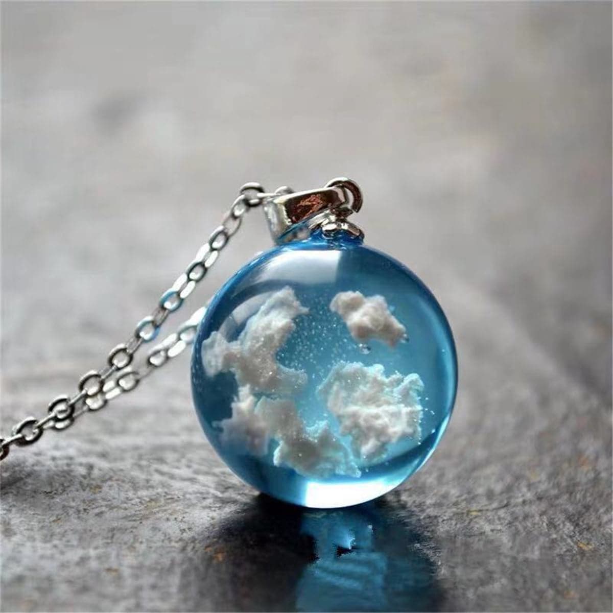 Blue topaz pendant on a silver chain, featuring a cloud design, adds elegance to any outfit.