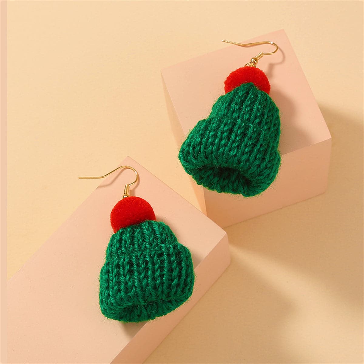 A pair of green and red knitted hats with pom poms, styled as festive Christmas accessories.