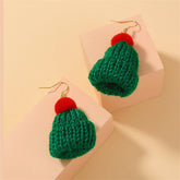 A pair of green and red knitted hats with pom poms, styled as festive Christmas accessories.