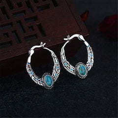 Elegant turquoise stone hoop earrings adorned with silver accents and feather designs, showcasing a vibrant color contrast.