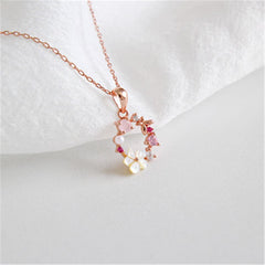 Stunning rose gold necklace with pink flowers and white stones, highlighted by a cubic zirconia and pearl flower pendant.