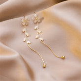 Gold plated floral drop earrings featuring Cats Eye and sparkling Cubic Zirconia accents. Elegant and eye-catching design.