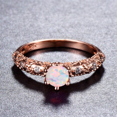 Elegant rose gold ring featuring a round opal stone, adorned with sparkling cubic zirconia accents.