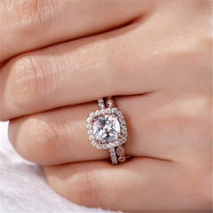 Chic rose gold engagement ring featuring a cushion-cut diamond and a halo of cubic zirconia, along with a stylish band.