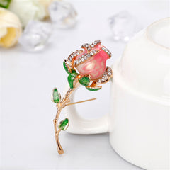 Opulent pink rose brooch with verdant green leaves, featuring exquisite 18K gold plating and dazzling cubic zirconia.