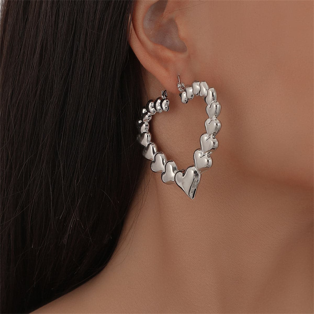 Silver heart-shaped hoop earrings, adding a charming flair to any outfit with their sleek design.