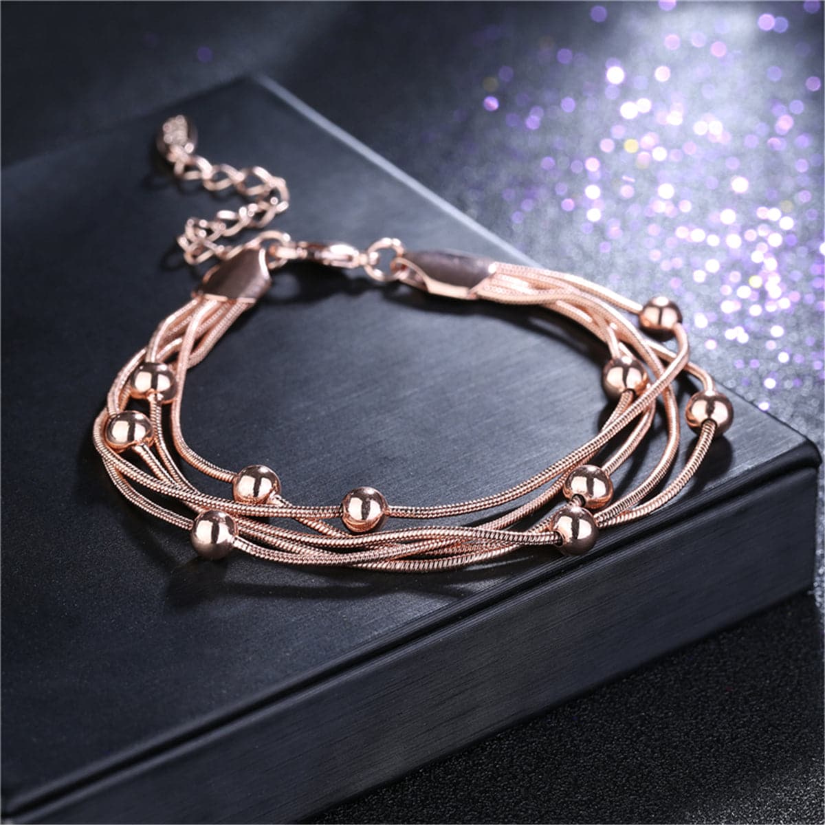 18K rose gold-plated bracelet featuring four strands of elegant beads, perfect for adding a touch of glamour to any outfit.