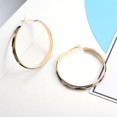 Elegant gold hoop earrings with a chic pattern of black and white dots, ideal for a fashionable accessory.