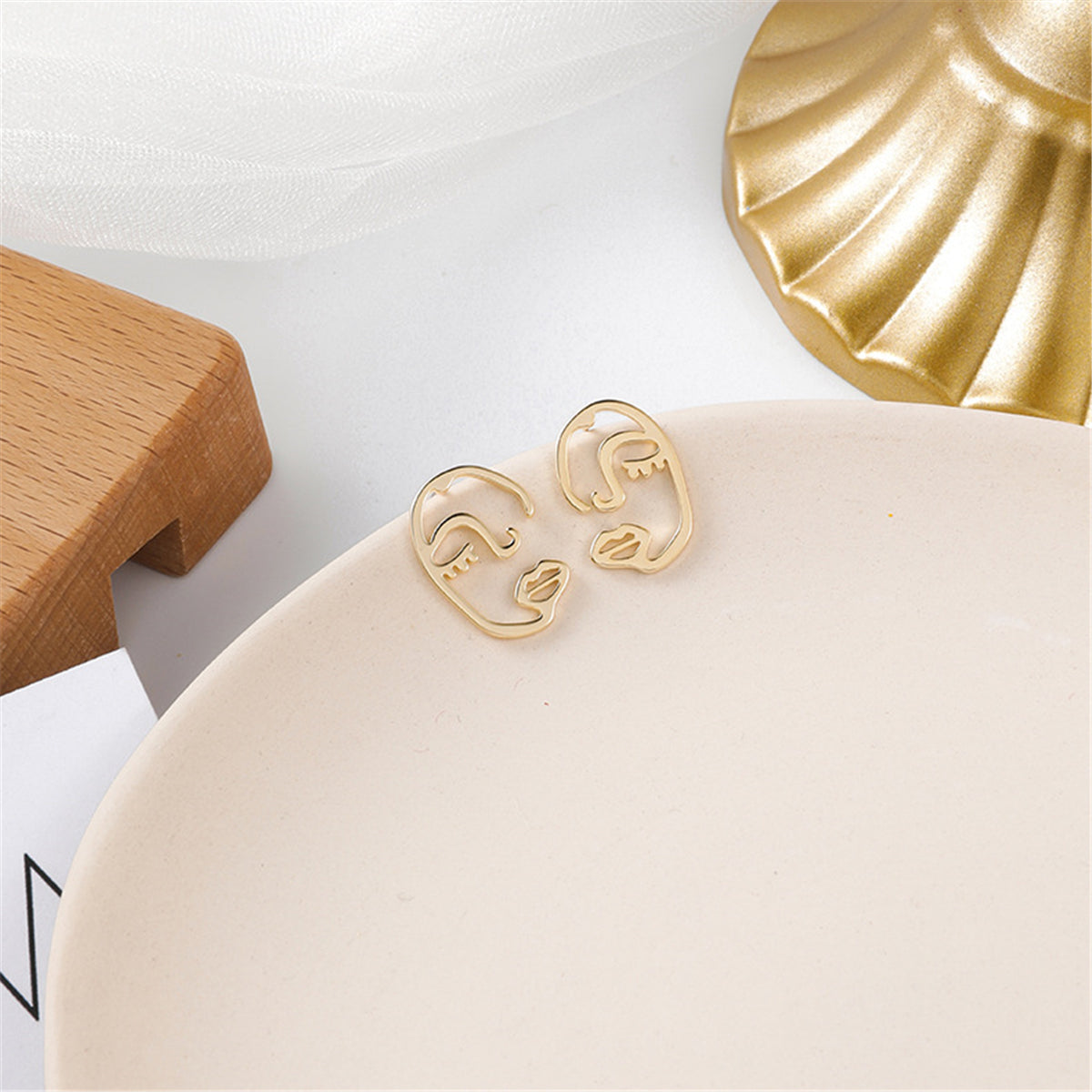 Elegant 18K gold-plated earrings showcasing abstract faces with intricate eyes, perfect for a stylish look.