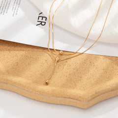 Beautiful 18K gold-plated lariat necklace adorned with two small charms, ideal for a chic and stylish look.