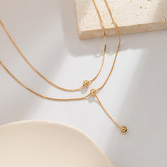 Dazzling 18K gold-plated bead drop lariat necklace showcasing two small charms, a perfect accessory for any occasion.