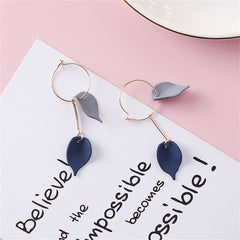 A pair of earrings with blue acrylic leaves and another with 18K gold-plated leaves, both offering a chic, nature-inspired look.