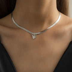 A woman showcases a silver butterfly charm on her snake chain choker, highlighting its elegant design.