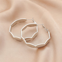 A pair of silver-plated wave hoop earrings with a unique curved shape.