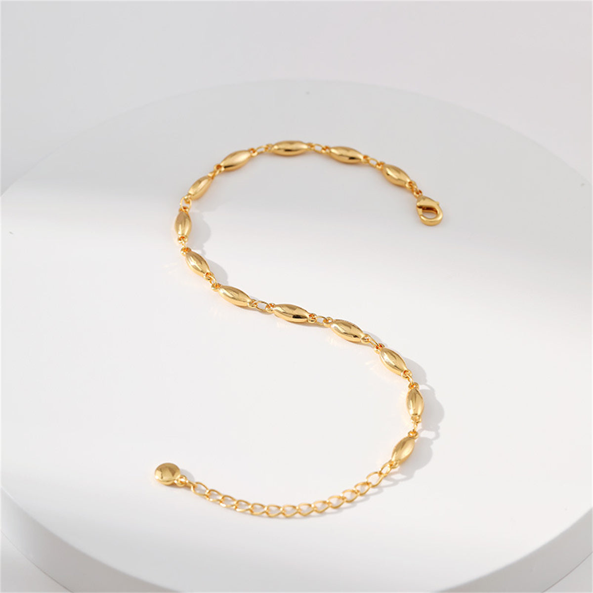 A gold bracelet featuring small oval beads, elegantly designed as an 18K gold-plated olive chain bracelet.