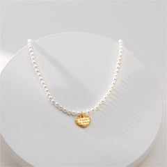 A gold heart charm on a white pearl necklace, featuring an 18K gold-plated 'Love You' pendant.