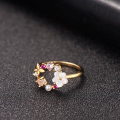 Stunning gold-plated ring with pink floral accents and white stones, designed in a delicate open-circle style.