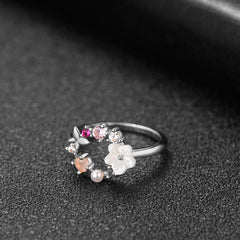 A charming floral ring in silver, featuring a white flower and pink cubic zirconia, accented by a butterfly for a whimsical touch.