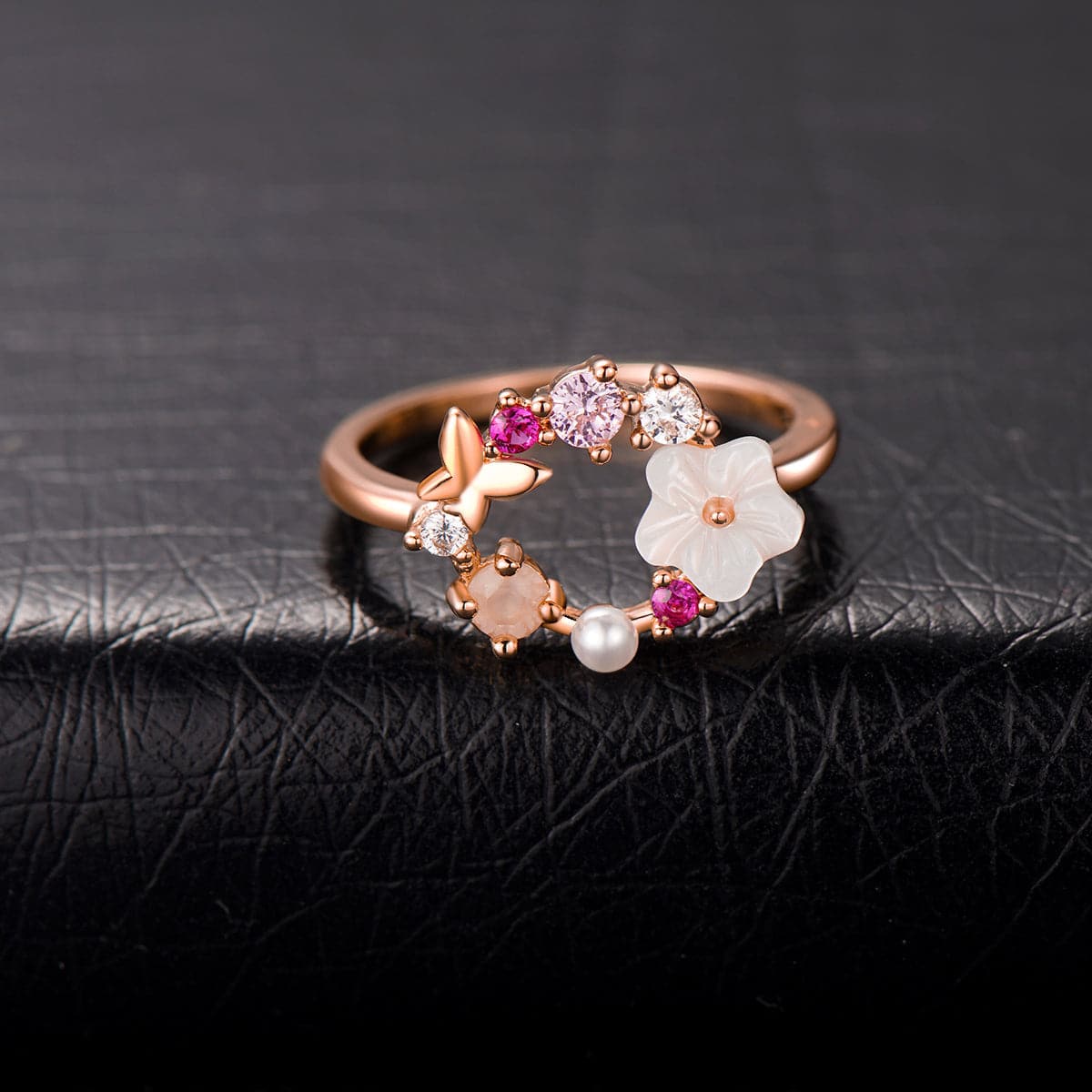 Rose gold ring featuring pink flowers and white stones, designed as an open-circle floral piece in 18k rose gold plating.