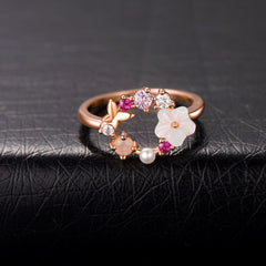 Rose gold ring featuring pink flowers and white stones, designed as an open-circle floral piece in 18k rose gold plating.