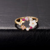 Gold-plated floral ring featuring pink flowers and white stones in an open-circle design, elegant and eye-catching.