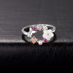 A silver-plated floral ring featuring a white flower design, pink cubic zirconia stones, and a delicate butterfly accent.