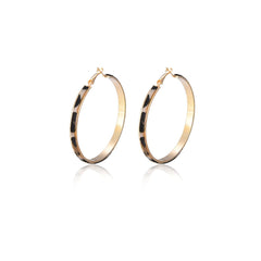 Trendy gold hoop earrings with a striking black and white dotted pattern, perfect for a bold fashion statement.