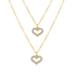 Two shimmering gold heart pendants with diamonds, part of a layered necklace crafted from 18K gold-plated and cubic zirconia.