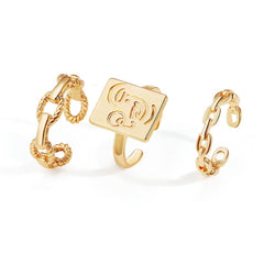 A chic set of three gold-plated rings featuring initials, complemented by a trendy chain for a unique accessory look.