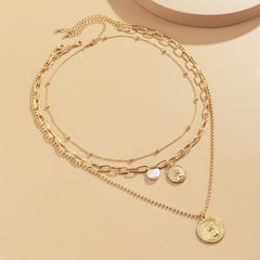 Stylish layered necklace with a gold coin charm and pearl accents, featuring a fine cable chain design.