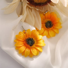 Vibrant yellow sunflower earrings with black centers, designed as stylish drop earrings for a cheerful look.