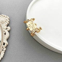 Three personalized gold-plated rings with initials, beautifully connected by a chain, showcasing modern elegance and style.