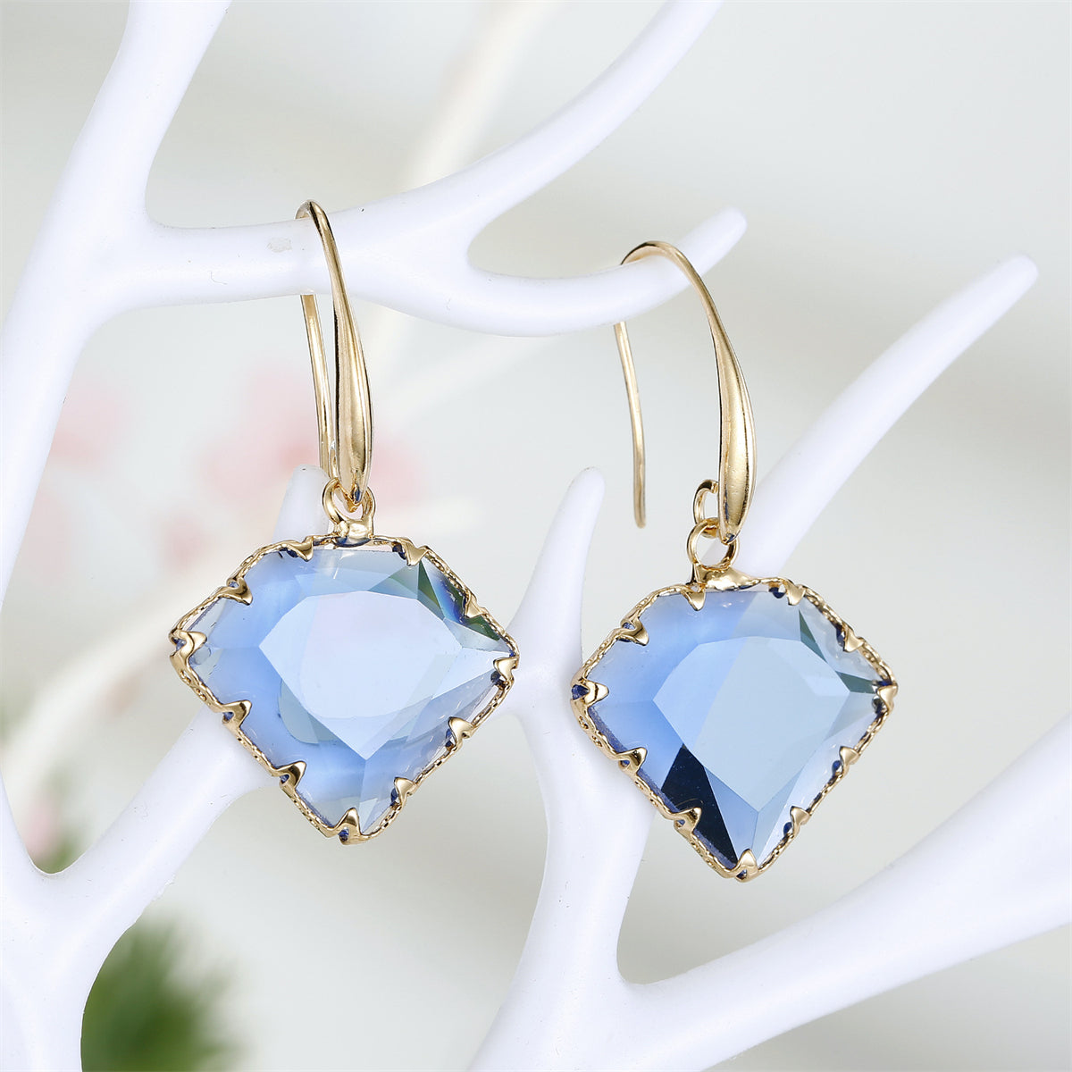 Stunning blue crystal earrings featuring a diamond shape, beautifully complemented by 18K gold plating for a chic look.