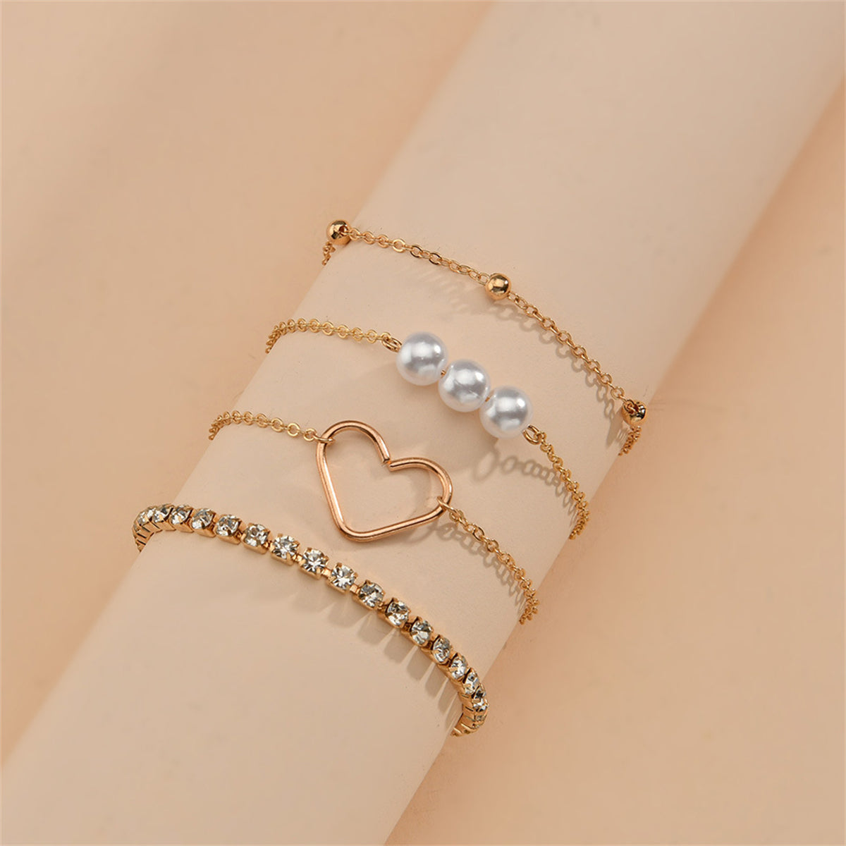 Elegant display of three gold chains with pearls and heart charms, complemented by a stunning 18K gold-plated tennis bracelet set.
