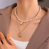 A layered necklace featuring an 18K gold-plated heart and sun coin design, elegantly crafted with pearls.