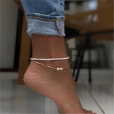 A gold chain anklet featuring a pearl and gold beads, part of a luxurious 18K gold-plated anklet set.