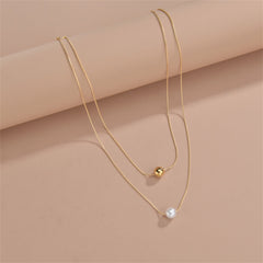 Two exquisite gold and white pearls on a stylish chain, part of a layered necklace with 18K gold-plated beads.