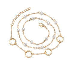 A stylish bracelet composed of a gold chain, pearls, and a circle charm, crafted in 18K gold plating for a luxurious look.