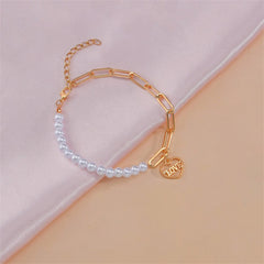 A refined bracelet of white pearls with a gold heart charm, symbolizing love and grace in a timeless design.